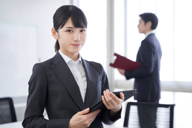 オフィスで笑顔の日本人女性 - スーツ ストックフォトと画像