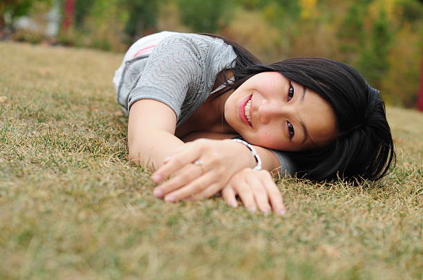 Smiling lady laying down on grass stock photo