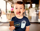 istock Smiling little boy licking messy chocolate from his face 1348673017