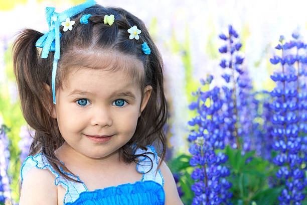 smiling little girl with blue eyes in flowers stock photo