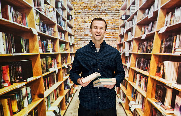 Smiling male bookseller in library stock photo