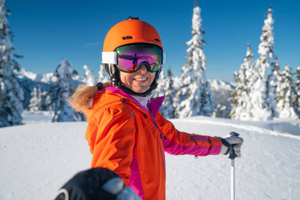glimlachend volwassen volwassen sportieve skiën vrouw kijkt terug naar de camera - posing with ski stockfoto's en -beelden