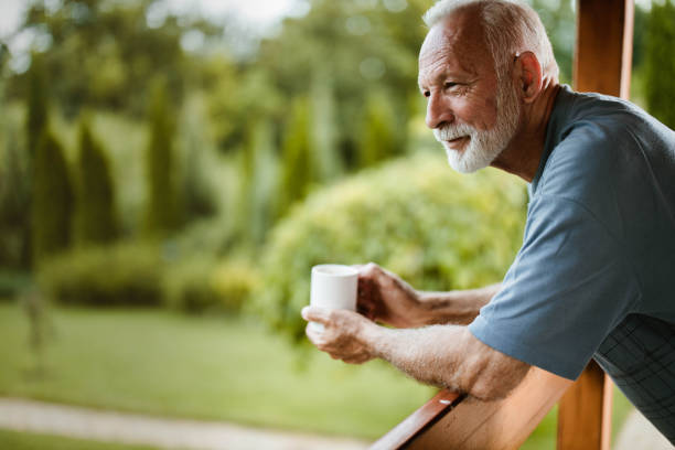Smiling mature man enjoying in morning coffee on a terrace. Senior man having his morning coffee on a balcony and day dreaming. Copy space. sunday coffee stock pictures, royalty-free photos & images