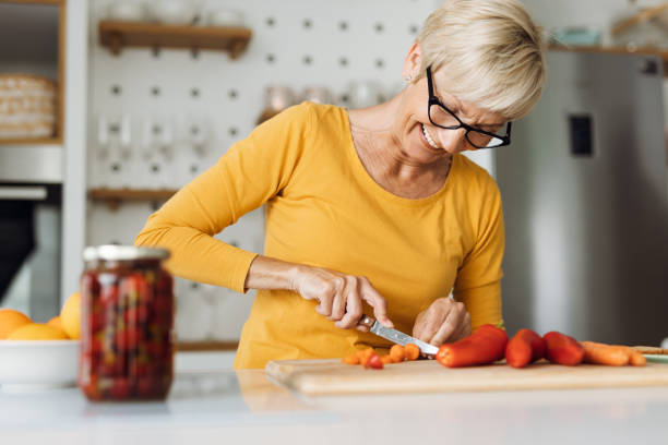 Smiling mature woman preparing healthy food in the kitchen stock photo