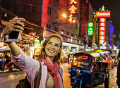 Smiling mature woman taking selfie self portraits in Chinatown while on vacation in Bangkok, Thailand