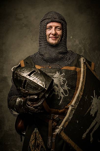 Smiling medieval knight  holding helmet stock photo