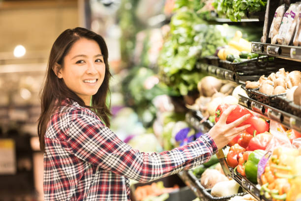 Smiling mid adult asian woman Smiling mid adult asian woman looking at the camera shopping for food in a supermarket filipino woman stock pictures, royalty-free photos & images