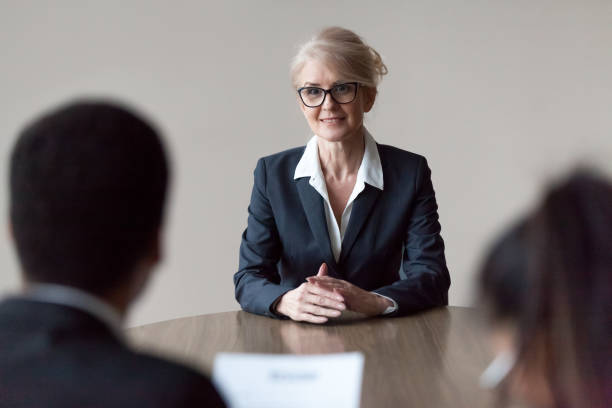 Smiling middle-aged female job applicant making first impression at interview Smiling middle aged senior female job applicant listening to hr questions making first impression at interview, recruiters interviewing older mature candidate, recruitment, age and employment concept prejudice stock pictures, royalty-free photos & images