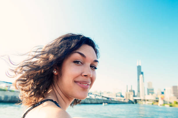 Smiling Millennial Hispanic Woman by Chicago Skyline Enjoying Tour A beautiful, millennial Puerto Rican woman in her 20's stands by Lake Michigan in Chicago, Illinois, a major USA city in the Midwest. She looks out over the water with the famous skyline behind her. hot puerto rican woman stock pictures, royalty-free photos & images