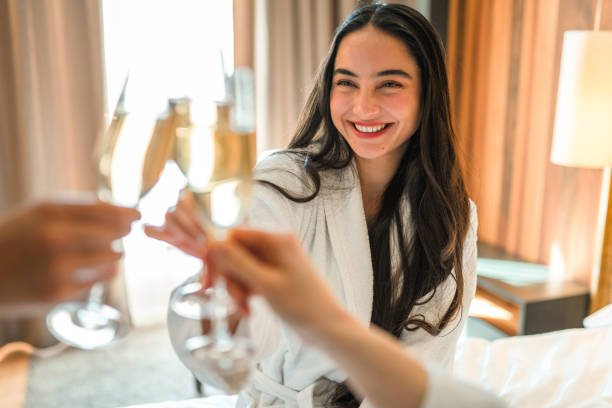 Smiling Mixed Race Women In Bathrobes Clinking With Champagne Glasses stock photo
