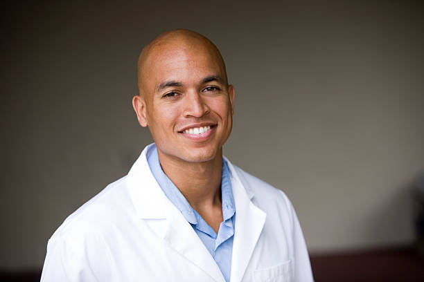Smiling mixed race young man wearing lab coat stock photo