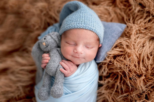 Smiling newborn holding toy while sleeping stock photo