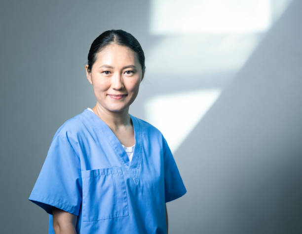 smiling nurse standing against wall at hospital - doctor wall imagens e fotografias de stock