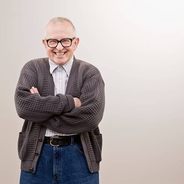 Smiling older man in sweater with arms crossed stock photo