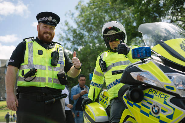 Smiling Police at an Edinburgh Parade A policeman on foot and another on a motorcycle smile and give a thumbs-up whilst patroling at an Edinburgh street parade theasis stock pictures, royalty-free photos & images
