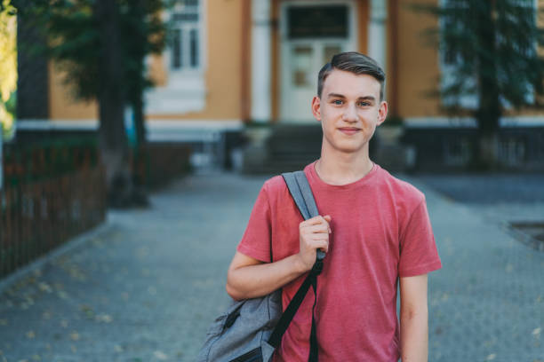 Smiling schoolboy in the schoolyard Portrait of confident student back to school high school building stock pictures, royalty-free photos & images