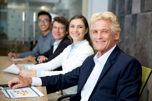 Smiling senior leader at meeting with his team stock photo