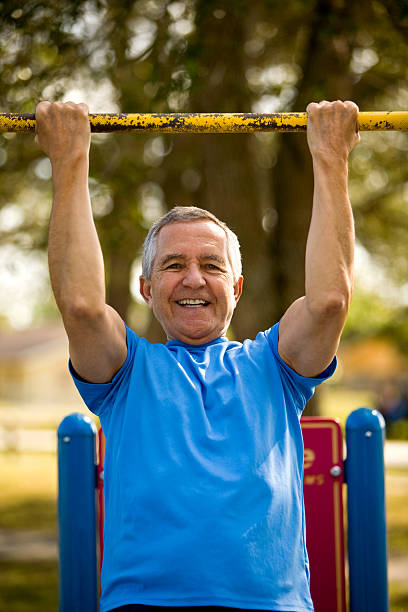 Smiling senior man at park doing a pull up stock photo