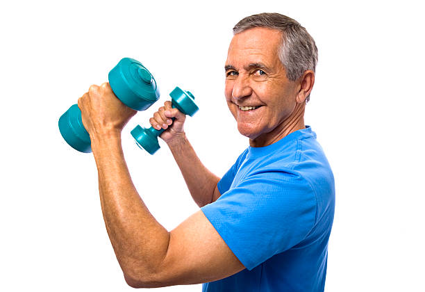 Smiling senior man holding dumbbells flexing biceps stock photo