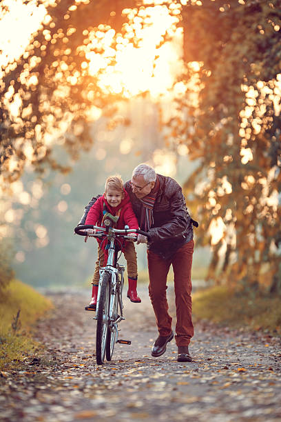 senior sorridente homem ensinando seu neto como ciclo. - grandparents vertical imagens e fotografias de stock