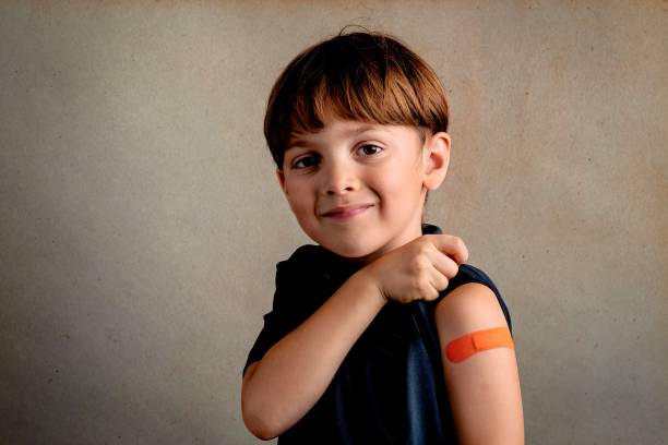 Smiling Six years old child just after being vaccinated showing a ban aid on his arm stock photo