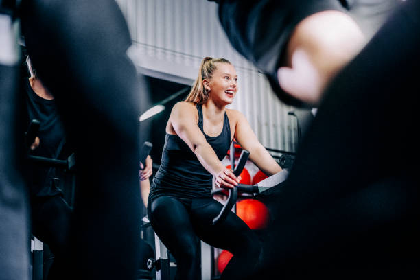 Smiling sporty woman cycling at health club stock photo
