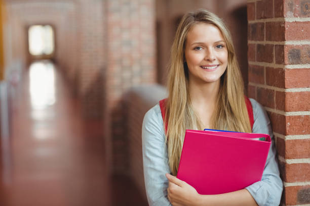 Smiling student with binder posing Smiling student with binder posing in the hallway 16 17 years stock pictures, royalty-free photos & images