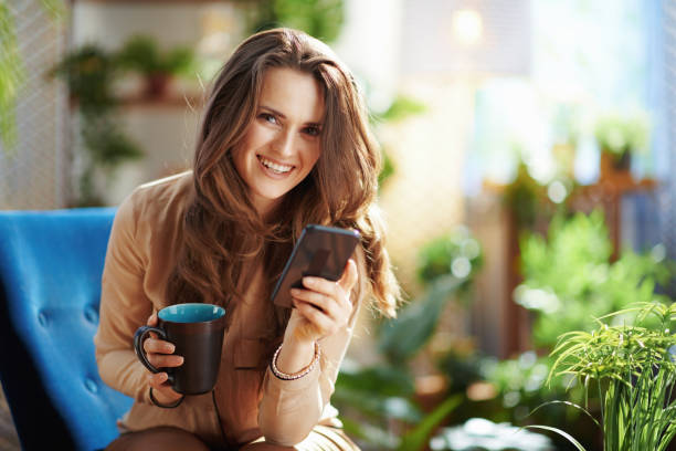 smiling stylish woman in sunny day using phone applications stock photo