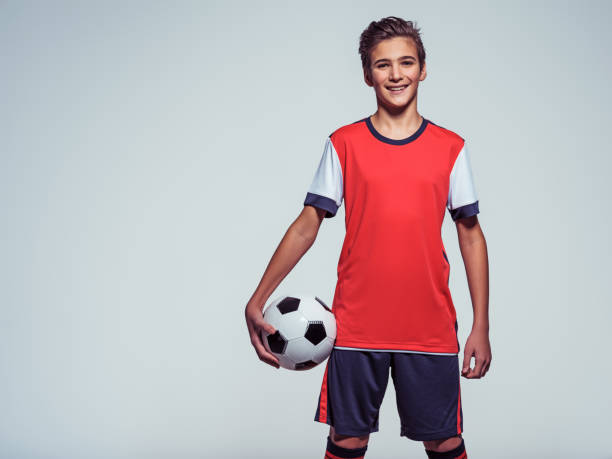 smiling teen boy in sportswear holding soccer ball stock photo
