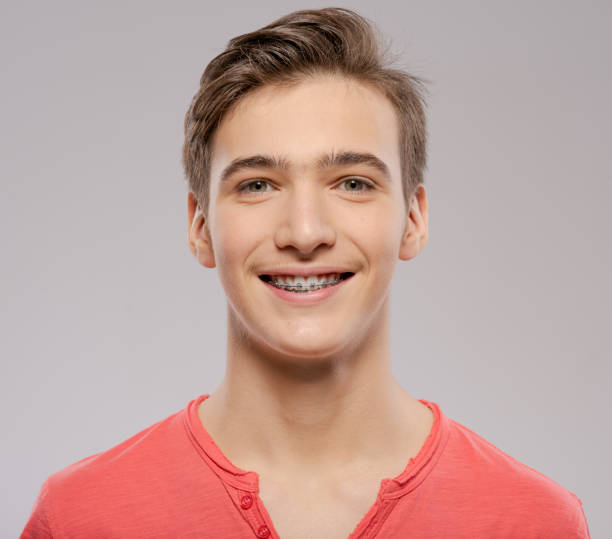 Smiling teen boy with braces on his teeth. Close-up portrait of a beautiful young boy with even healthy teeth. stock photo