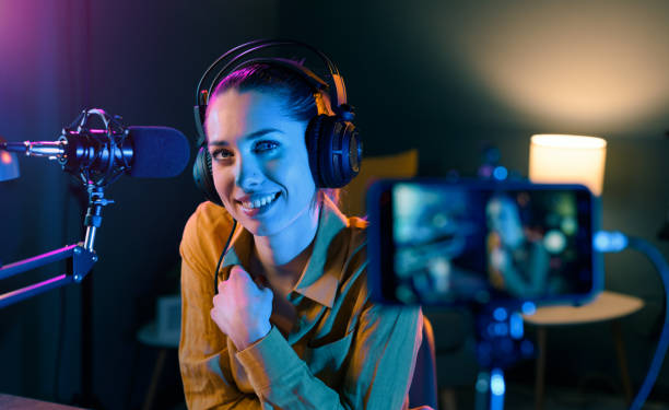 Smiling video blogger recording in the studio Smiling video blogger working in her studio, she is recording a video using her smartphone vlogging stock pictures, royalty-free photos & images