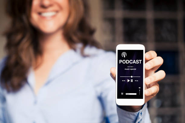 Smiling woman holding a mobile phone with podcast app in the screen. stock photo