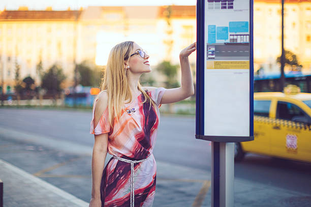 Smiling  woman in the city is checking the timetable in the bus stop