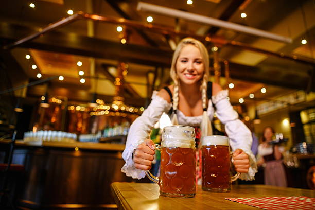Smiling woman in uniform Young waitress with beer in bar oktoberfest stock pictures, royalty-free photos & images