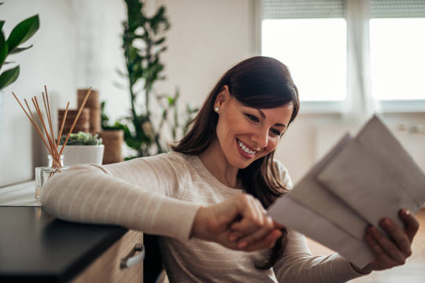 Smiling woman looking at received mail at home, close-up. Smiling woman looking at received mail at home, close-up. mail stock pictures, royalty-free photos & images