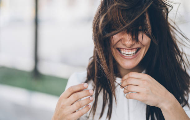 Smiling woman on a windy day Beautiful charming woman with messy hair laughing outdoor in windy day imperfection stock pictures, royalty-free photos & images