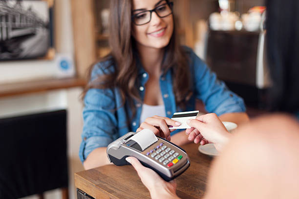 Smiling woman paying for coffee by credit card Smiling woman paying for coffee by credit card  credit card purchase stock pictures, royalty-free photos & images