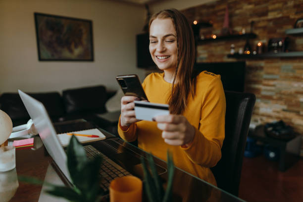 Smiling woman shopping online from home with a credit card stock photo