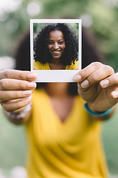 Smiling woman showing selfie Portrait of beautiful mixed-race woman showing self portrait holding photos stock pictures, royalty-free photos & images
