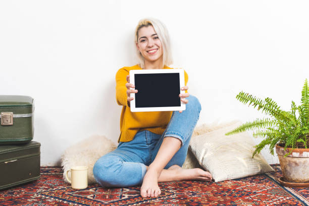 Smiling woman showing tablet pc while looking camera stock photo