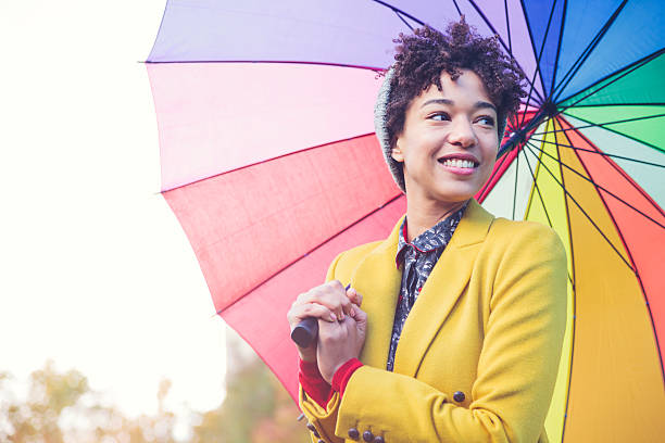 smiling woman under colorful umbrella (london, uk) - rain woman sun stockfoto's en -beelden
