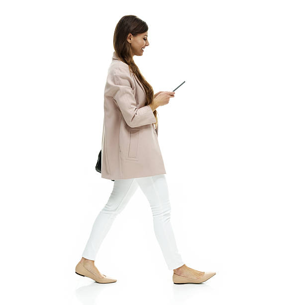 Smiling woman using phone and walking stock photo