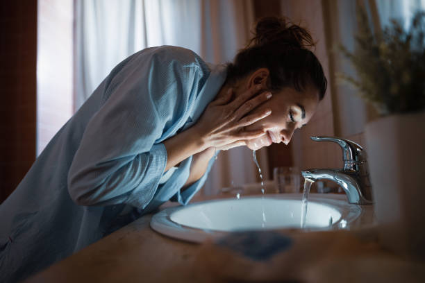 Smiling woman washing her face in the evening. Young smiling woman washing face in the bathroom. routine stock pictures, royalty-free photos & images