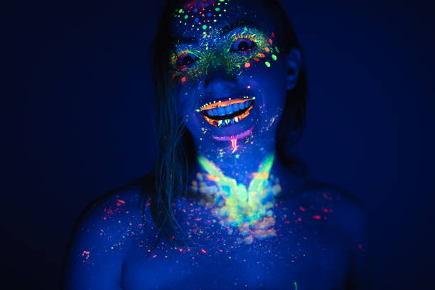 Smiling woman with fluorescent makeup Smiling, young, woman covered with fluorescent makeup. paint neon color neon light ultraviolet light stock pictures, royalty-free photos & images