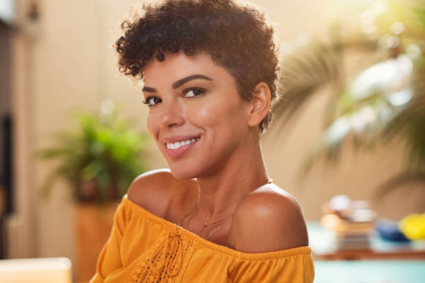 Smiling young african woman Portrait of natural beautiful girl smiling and looking at camera. Closeup face of brazilian young woman with curly hair. Charming african woman sitting at cafeteria. brazilian ethnicity stock pictures, royalty-free photos & images