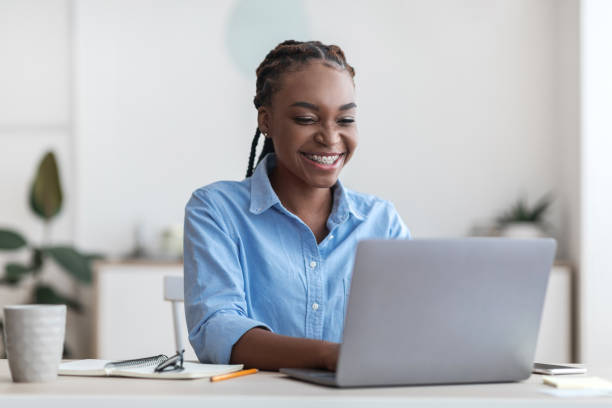 Smiling Young Black Trainee Woman Sitting At Workplace In New Office Smiling Young Black Trainee Woman Sitting At Workplace In New Office, Cheerful African American Female Employee Working On Laptop Computer, Typing On Keyboard, Answering Emails, Free Space trainee stock pictures, royalty-free photos & images
