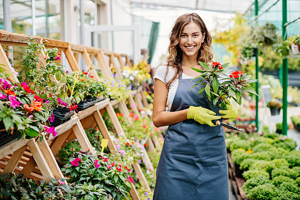 Smiling young gardener Attractive young woman in a flower center. garden center stock pictures, royalty-free photos & images