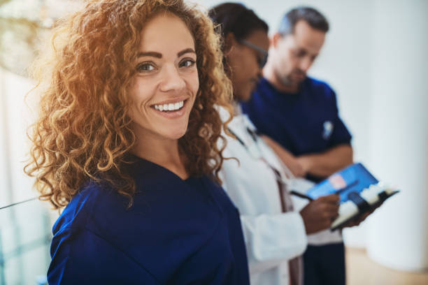 Smiling young medical intern standing with doctors in a hospital stock photo