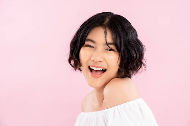 Smiling young pretty Asian woman with Korean short hairstyle Smiling young cute Asian woman with Korean short hairstyle in soft pink background chinese girl hairstyle stock pictures, royalty-free photos & images