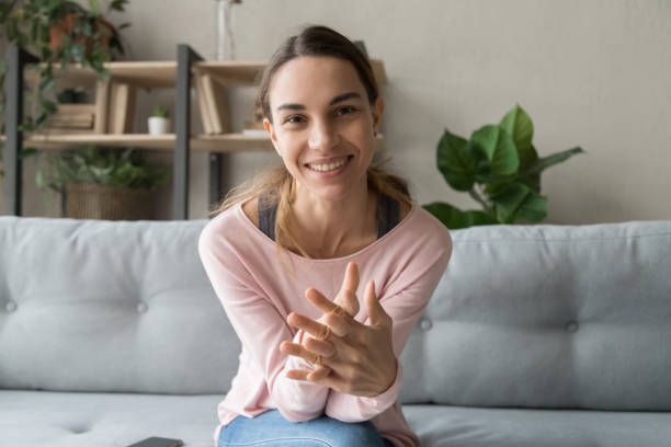 Smiling young woman blogger sit on sofa looking at camera Smiling young woman blogger influencer sit on sofa looking at camera make video conference call recording vlog at home, happy girl vlogger do online chat shooting blog at home, portrait, webcam view cams.con stock pictures, royalty-free photos & images